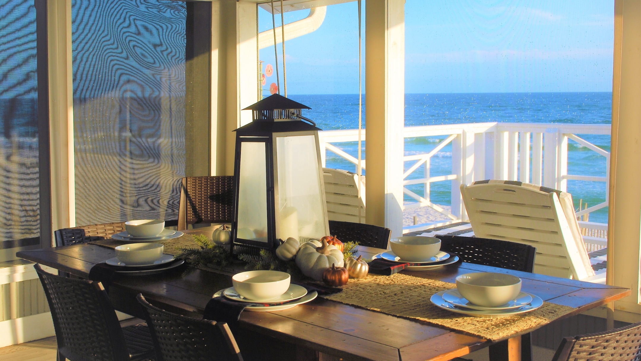 Dining table set for a holiday meal on a balcony overlooking the ocean.